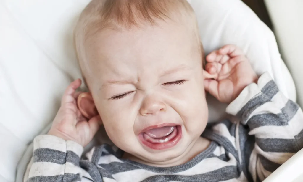 fotografía de niño llorando tocandose las orejas por causa de una otitis