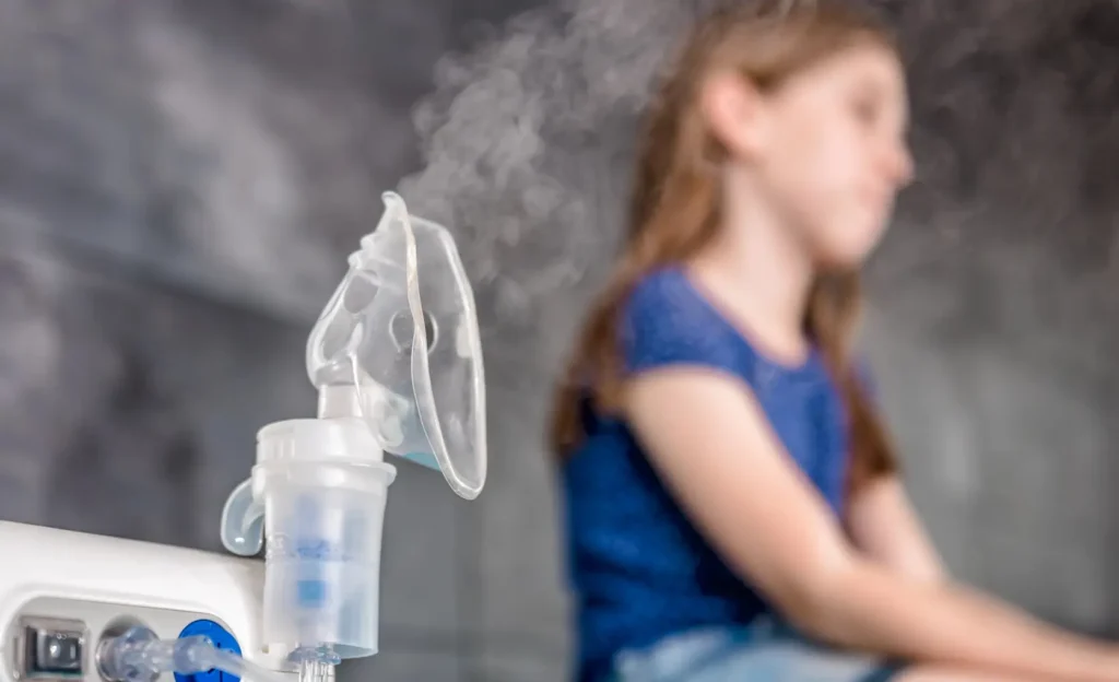 fotografía de un nebulizador encendido nebulizando suerlo fisiologico en primer plano, una paciente desenfocada detrás