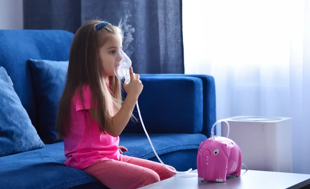 Imagen de una ñiña sentada en el sofa de su casa, en una sesión de nebulización con suero isotónico