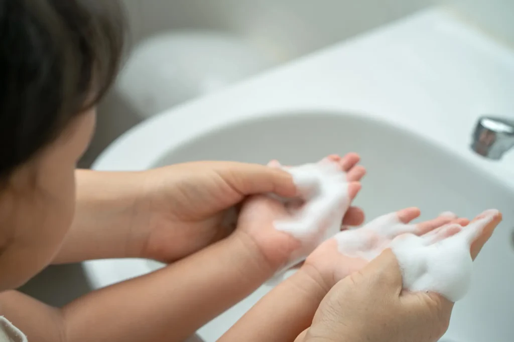 Fotografía detalle de una madre lavandole las manos a su hijo para prevenir resfriados por rhinovirus