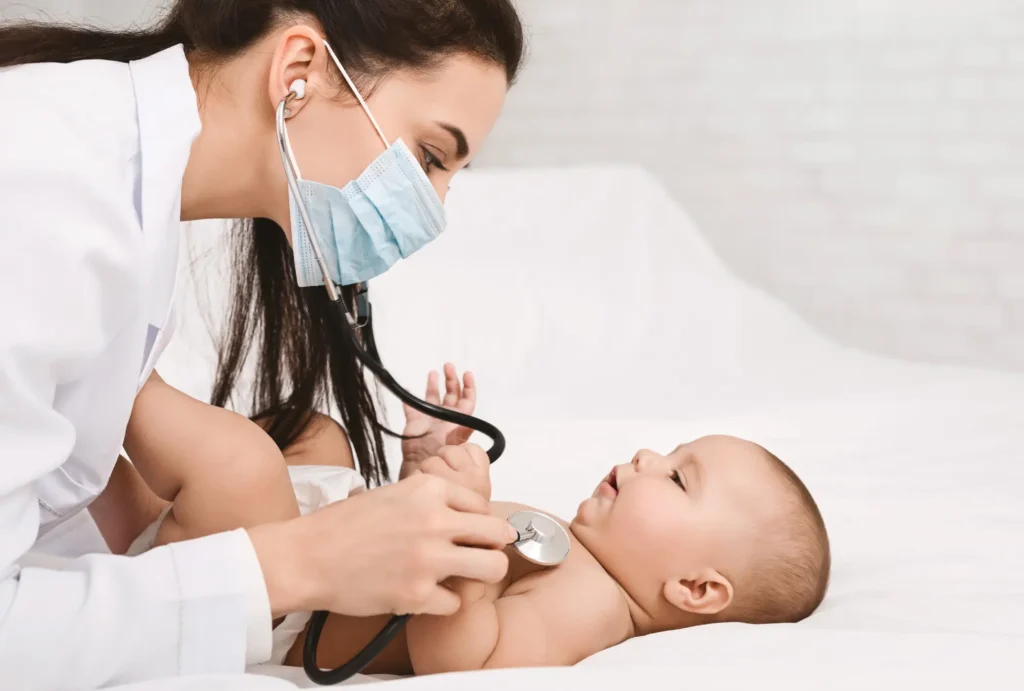 Fisioterapeuta respiratorio pediatrica auscultando un bebe en consulta clinica